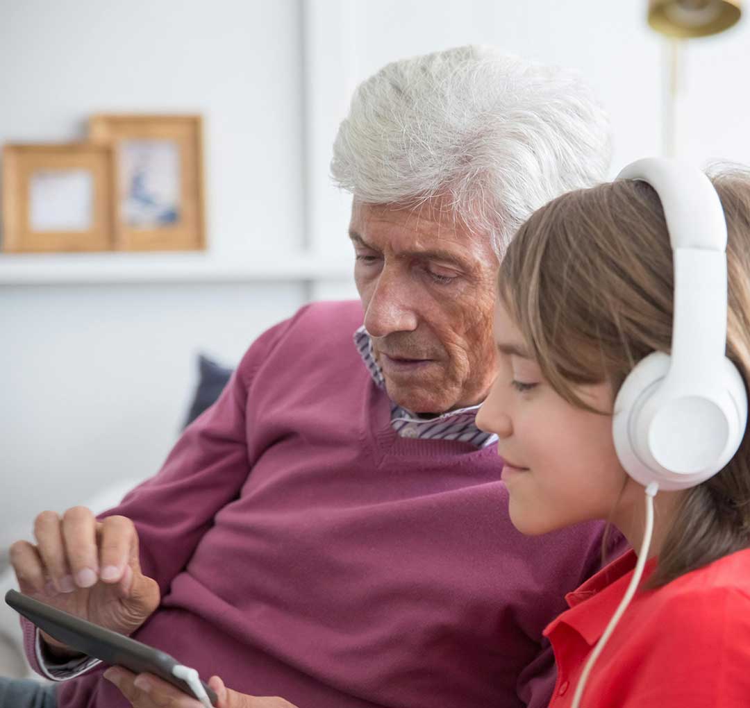 Specialized Skills: AAC and Communication Therapy Grandfather and grandson using an AAC device together, demonstrating specialized communication therapy support.